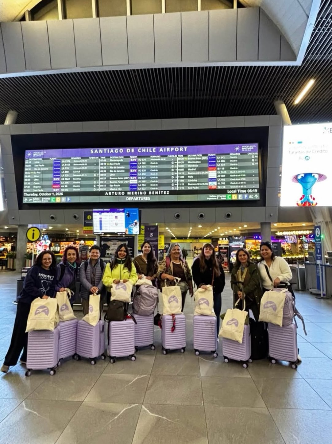 Grupo de viajeras en el aeropuerto de Santiago con maletas lilas